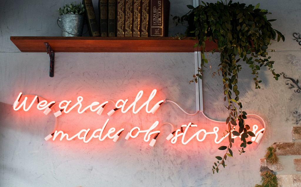 Neon lighting that reads We are all made of stories